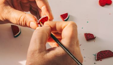 Handen boetseren kleine watermeloentjes van polymeerklei op tafel, een makkelijk beginnersproject voor sieraden