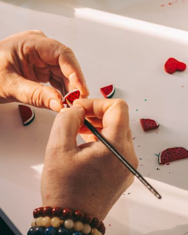 Handen boetseren kleine watermeloentjes van polymeerklei op tafel, een makkelijk beginnersproject voor sieraden